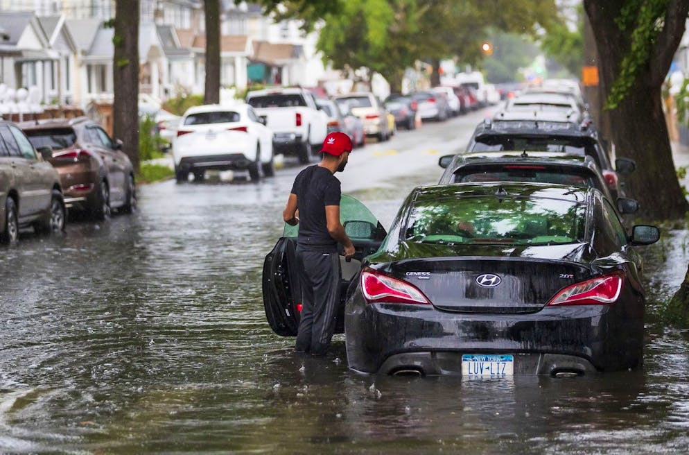 Balkar, de New York, regarde sa voiture inondée alors que la pluie de la tempête tropicale Henri tombe dans le Queens Borough de New York, New York, États-Unis, le 22 août 2021.