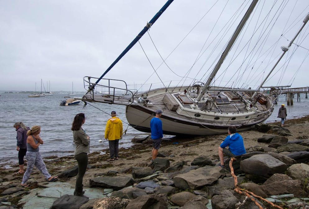 Les spectateurs regardent un voilier échoué par la tempête tropicale Henri à Jamestown, Rhode Island, États-Unis, le 22 août 2021.