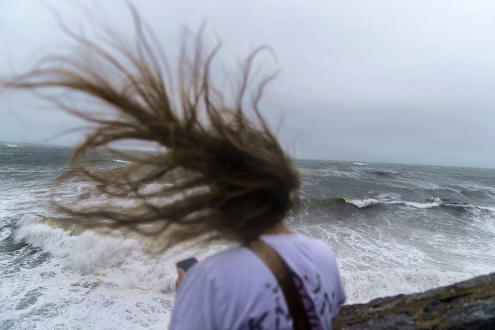 Strong surf from Tropical Storm Henri breaks along the Cliff Walk as a woman's hair blows in the wind in Newport, R.I., Sunday, Aug. 22, 2021. (AP Photo/David Goldman)