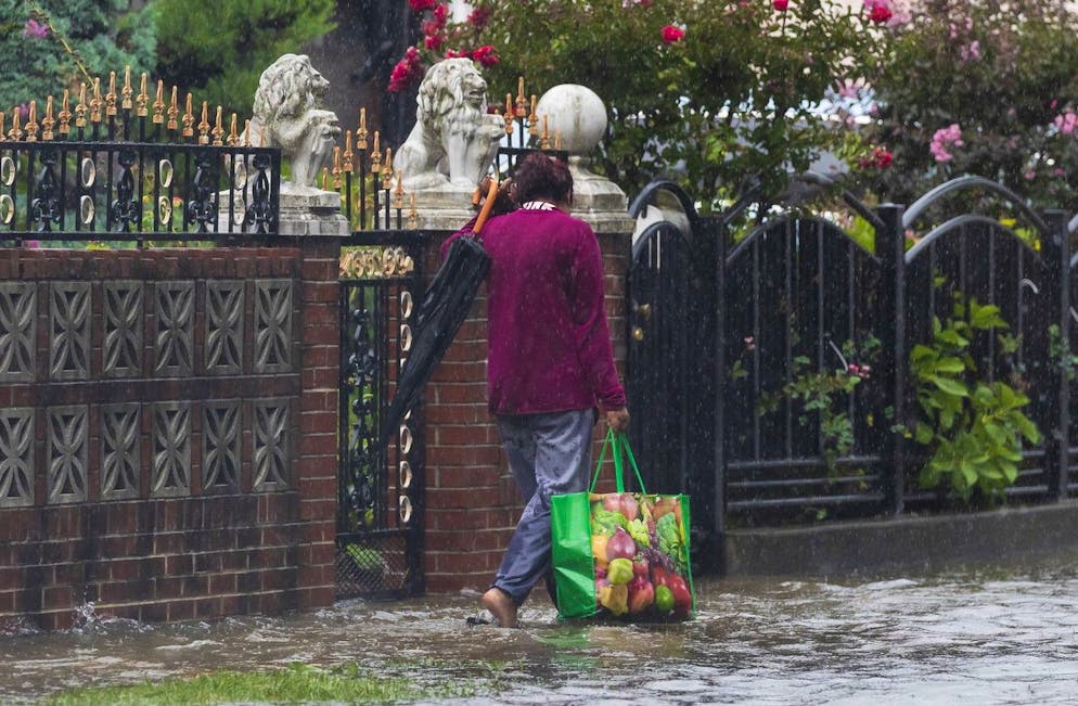 Une personne navigue sur un trottoir inondé alors que la pluie de la tempête tropicale Henri tombe dans le quartier Queens de New York, New York, États-Unis, le 22 août 2021.