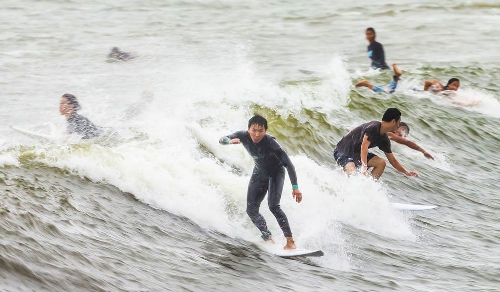 Les gens surfent sur les vagues soulevées par la tempête tropicale Henri à Rockaway Beach dans le Queens Borough de New York, New York, USA, 22 août 2021.