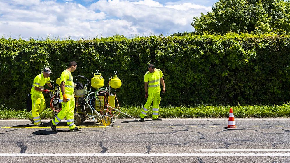 Arbeiter markieren eine Strasse: In Nidwalden sollen mehr Hauptstrassen mit Randlinien ausgestattet werden. (Symbolbild)