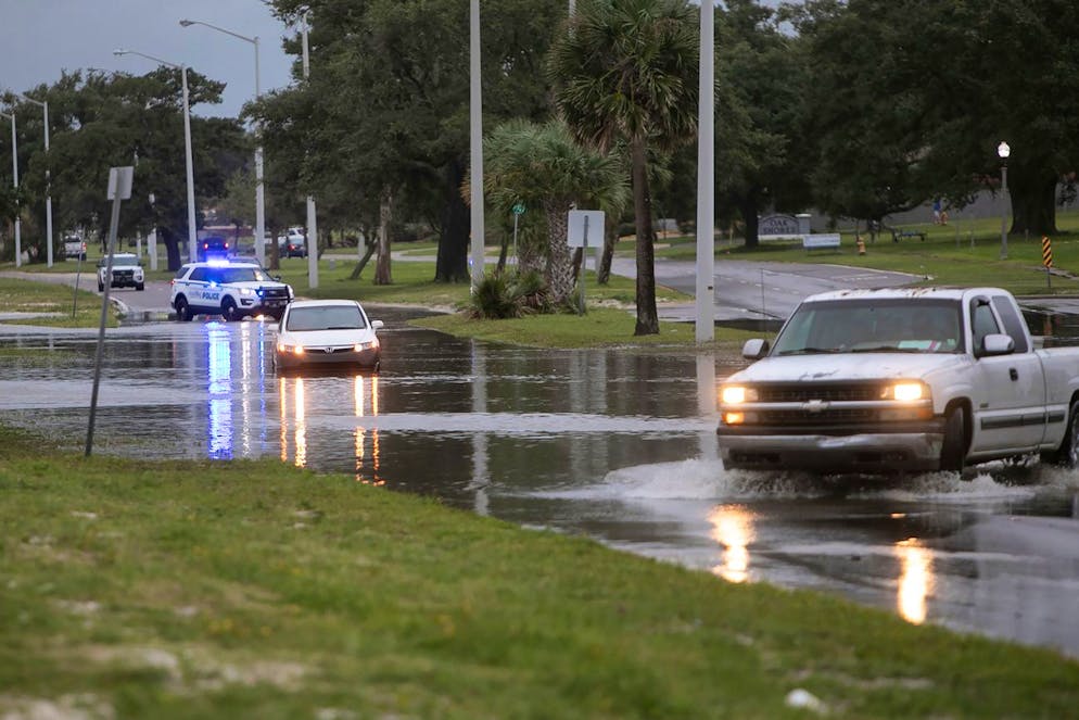 A Biloxi, Miss., police SUV blocks off traffic along U.S. 90 after a Honda Civic, stalled out in the middle of the street as it tried to drive through Hurricane Ida storm surge floodwater, Sunday, Aug. 29, 2021. (Justin Mitchell/The Sun Herald via AP)
