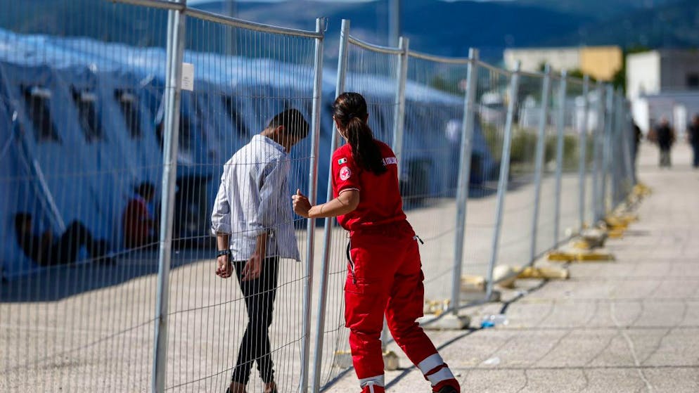 Ein geflüchteter Afghane geht an einem Zaun in einem Einsatzzentrum des italienischen Roten Kreuzes, Croce Rossa Italiana (CRI) in Avezzano. In dem Einsatzzentrum werden mit Hilfe der Armee und des Zivilschutzes afghanische Geflüchtete aufgenommen. Foto: Cecilia Fabiano/LaPresse via ZUMA Press/dpa