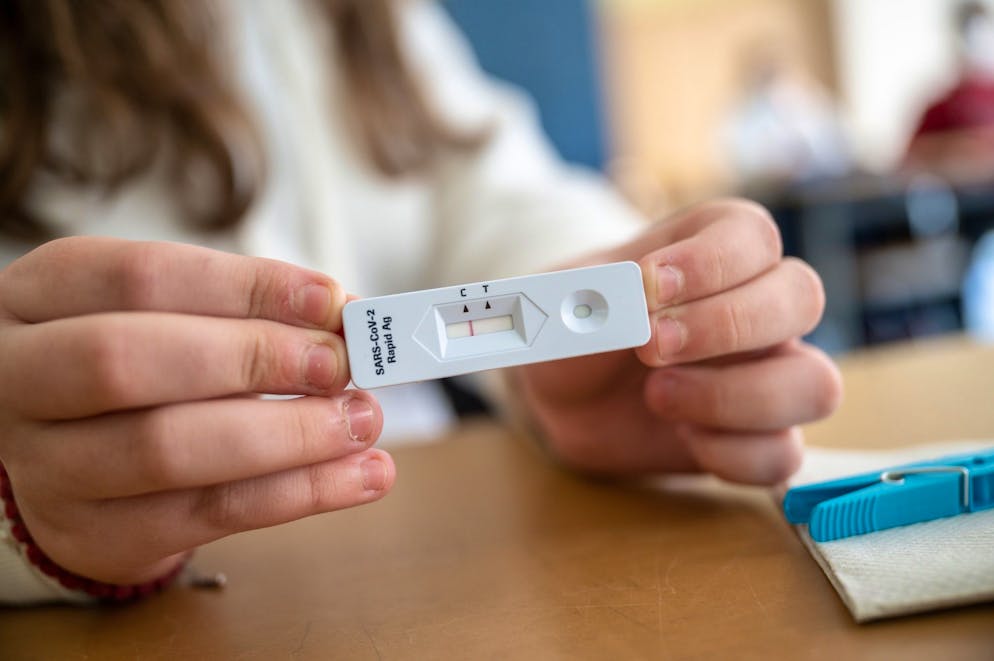 Eine Jufgendliche zeigt einen Corona-Selbsttest. (Sy