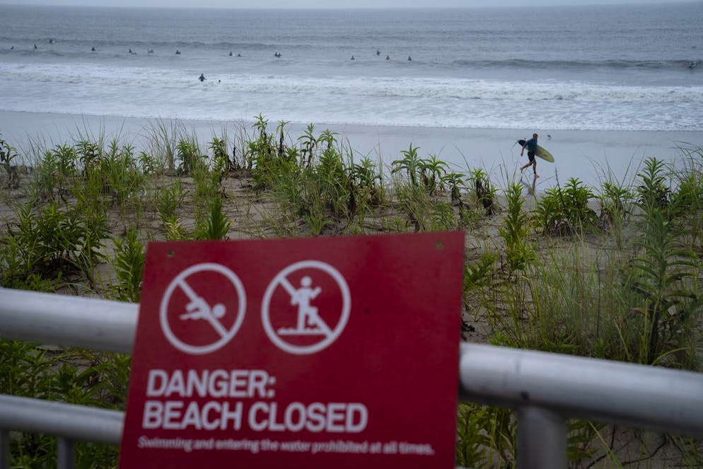 Surfers enjoy the waves on a closed beach as Tropical Storm Henri brings strong surf and high winds to the area, Sunday, Aug. 22, 2021, in the Rockaways neighborhood of the Queens borough of New York. (AP Photo/John Minchillo)