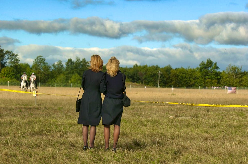 Two United flight attendants look to the actual crash site just before the start of the memorial service at the temporary memorial to Flight 93 near Shanksville, Pa., Wednesday, Sept. 11, 2002. (KEYSTONE/AP Photo/Julie Jacobson)