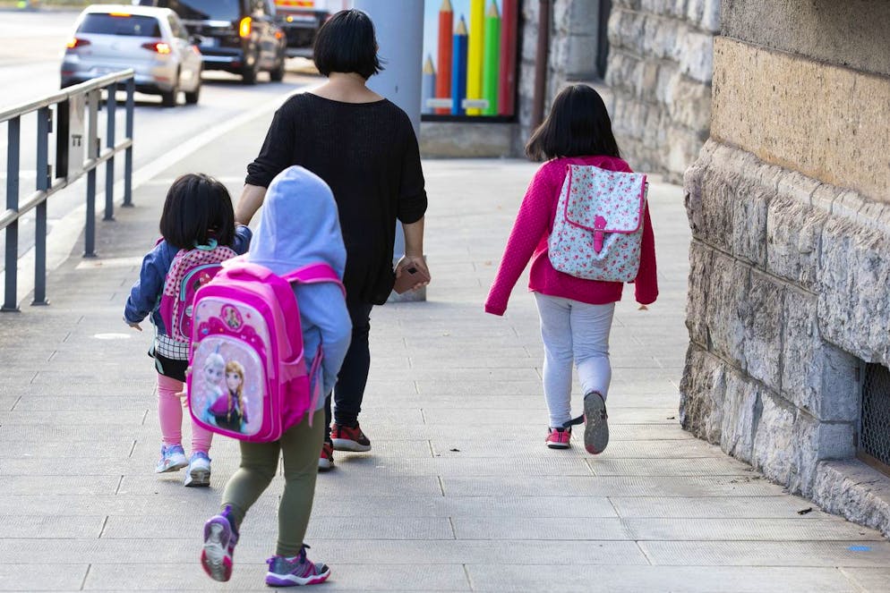 Des eleves portant leurs sacs d'ecole en compagnie de leur maman marchent pour se rendre a l'ecole primaire de Secheron, lors de la rentree scolaire 2021-22, ce lundi 30 aout 2021 a Geneve. (KEYSTONE/Salvatore Di Nolfi)