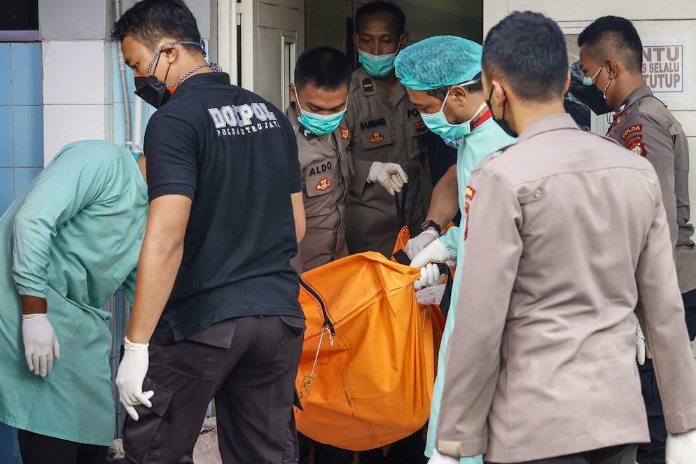 Des agents de police d'identification des victimes de catastrophe (DVI) portent un sac mortuaire à la suite d'un incendie de prison, dans un hôpital de Tangerang, Banten, Indonésie, le 08 septembre 2021.