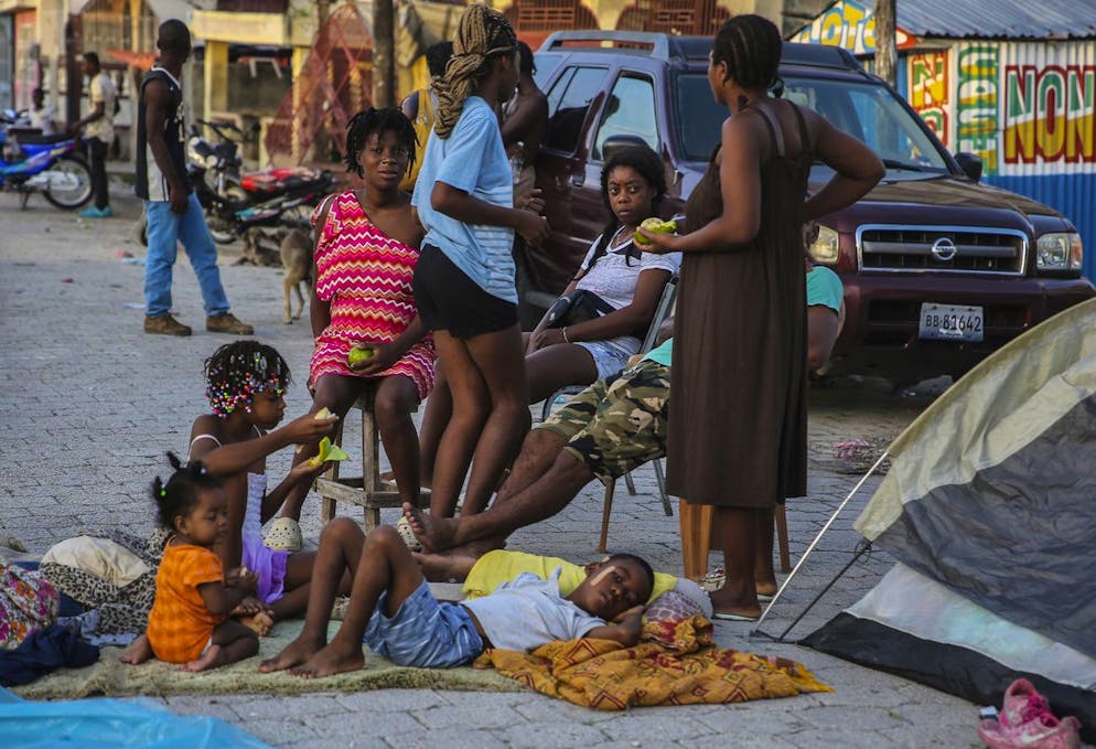 Locals eat after spending the night in the middle of a street after Saturday´s 7.2 magnitude earthquake in Les Cayes, Haiti, Sunday, Aug. 15, 2021. (AP Photo/Joseph Odelyn)