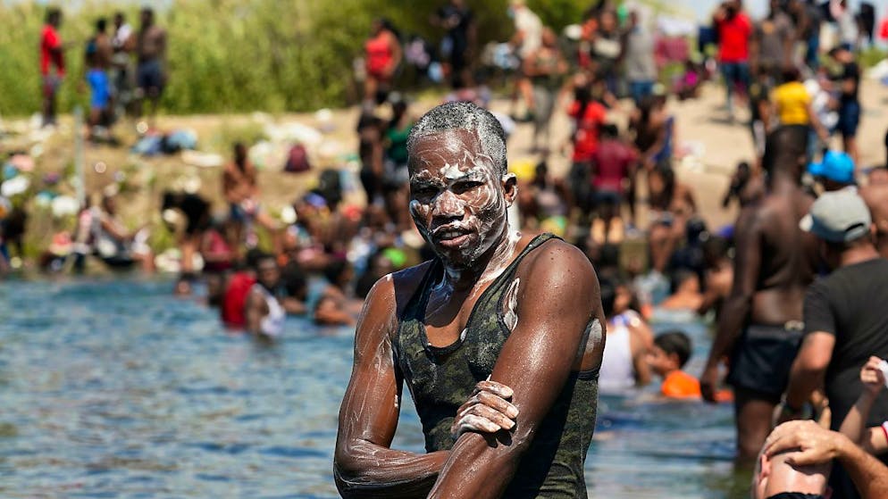 Ein haitianischer Migrant badet im Rio Grande nahe eines Dammes, an dem Migranten von Mexiko in die Vereinigten Staaten ein- und ausreisen. In der US-Grenzstadt Del Rio hat sich die Situation dramatisch zugespitzt. Dort harren Tausende Migranten unter einer Brücke aus. Foto: Eric Gay/AP/dpa