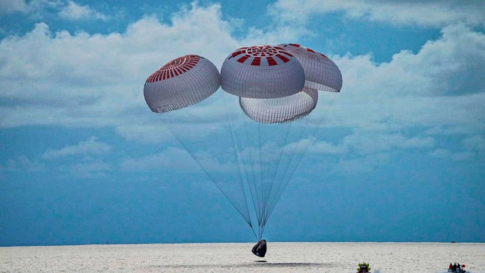Eine SpaceX-Kapsel mit vier Personen an Bord geht vor der Küste Floridas mit Fallschirmen in den Atlantik nieder. Foto: Uncredited/SpaceX via AP/dpa - ACHTUNG: Nur zur redaktionellen Verwendung und nur mit vollständiger Nennung des vorstehenden Credits bis 14 Tage nach Sendedatum.