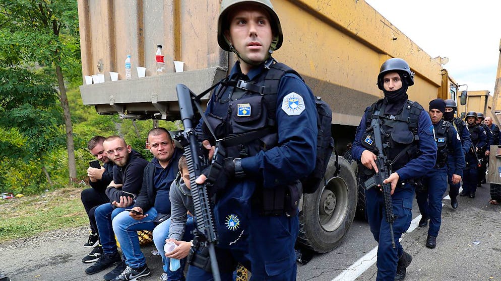 Kosovo-Polizisten patrouillieren an Lastwagen vorbei, wo Kosovo-Serben eine Straße in der Nähe des nördlichen Kosovo-Grenzübergangs Jarinje blockieren. Foto: Bojan Slavkovic/AP/dpa