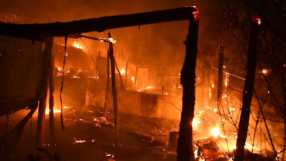 Feuer brennt außerhalb des überfüllten Flüchtlingslagers am Hafen von Vathy auf der ostägäischen Insel Samos, Griechenland. Am späten Sonntagabend ist aus bisher unbekannten Ursachen im alten Flüchtlingslager auf der griechischen Insel Samos in Brand ausgebrochen. Foto: Michael Svarnias/AP/dpa