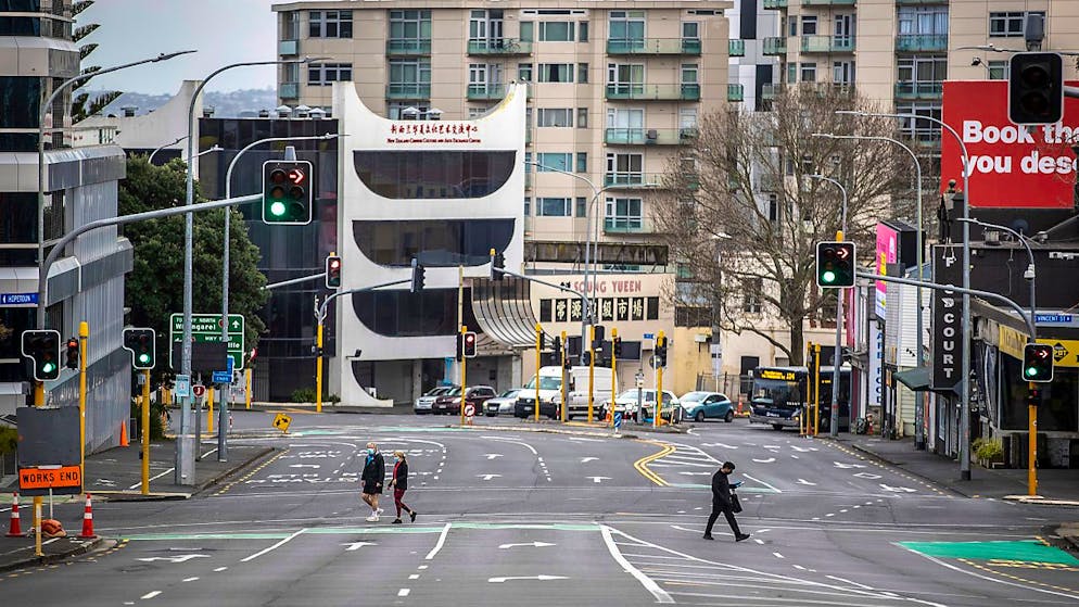 Menschen überqueren im zentralen Geschäftsviertel fast leere Straßen. Aufgrund von sinkenden Corona-Zahlen wird nach einem Monat des strengen Lockdowns in der neuseeländischen Millionenmetropole Auckland gelockert. Das teilte die Regierung am Montag mit. Foto: Michael Craig/New Zealand Herald/dpa