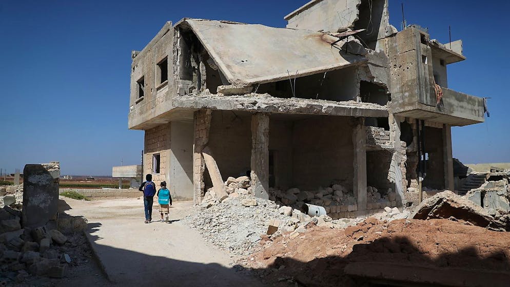 Kinder laufen an einem zerstörten Haus in Idlib vorbei, nachdem sie ihre Schule zu Beginn des Schuljahres verlassen haben. Foto: Anas Alkharboutli/dpa