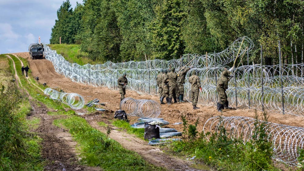Polnische Soldaten errichten einen Stacheldrahtzaun Grenze zu Belarus (Archiv).