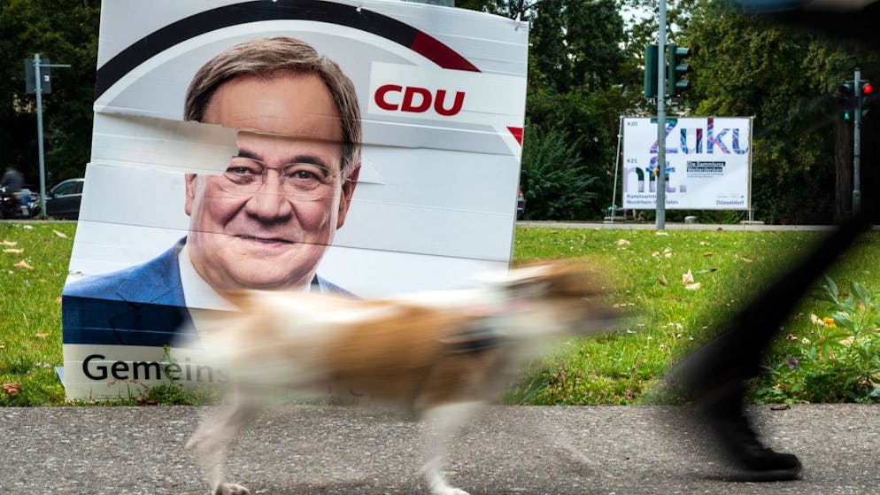 Ein Hund geht an einem beschädigten Wahlplakat vom Armin Laschet (CDU) vorbei. Foto: Federico Gambarini/dpa