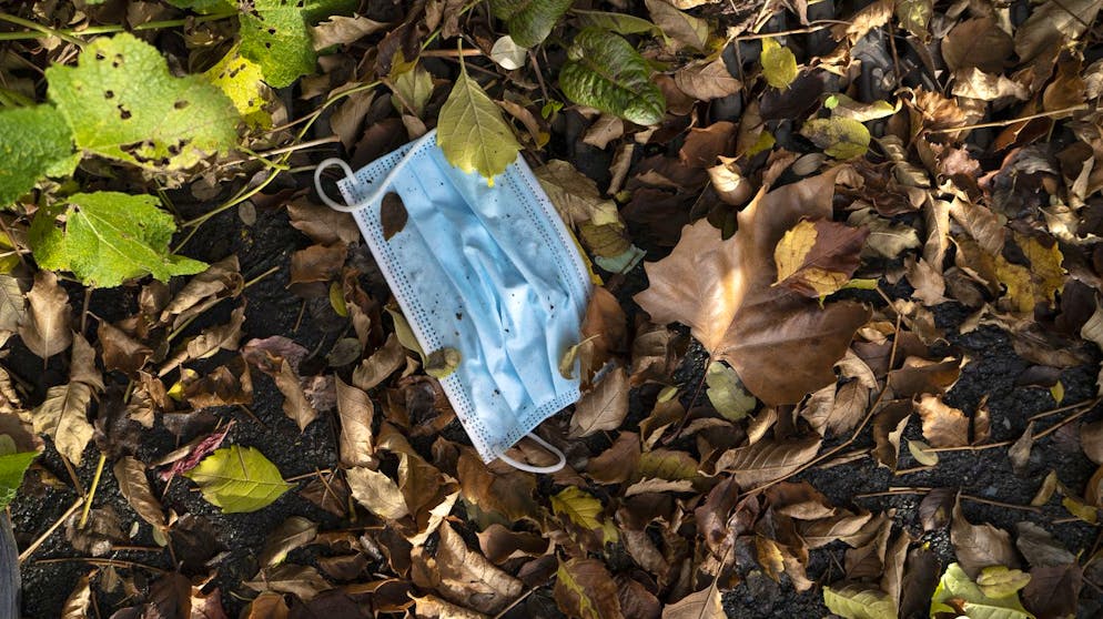 Eine nasse benutzte Hygienemaske liegt im nassen Herbstlaub weggeworfen auf dem Boden, fotografiert am 20. November 2020 in Zuerich. (KEYSTONE/Gaetan Bally)