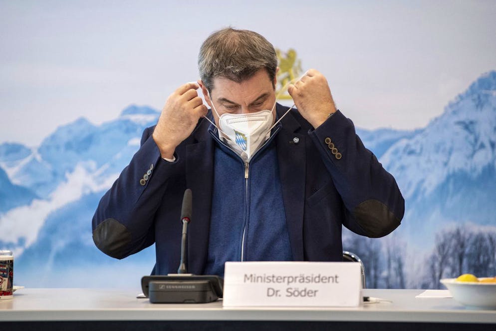 Markus Soeder, party chairman and Govenor of Bavaria, takes his seat in the State Chancellery in Munich, Germany, wearing an FFP2 protective mask at the beginning of a meeting of the Council of Ministers on Sunday, Dec. 6, 2020. Behind him, a large-format photo is shown showing the winter landscape around the Watzmann in the Berchtesgadener Land region. The cabinet, which meets via video link, focuses on the consequences of the Corona pandemic. (Matthias Balk/dpa via AP)