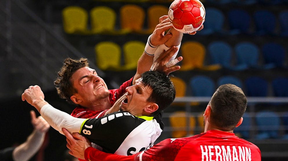 epa08937749 Switzerland's Andy Schmid (C) in action against Austria's Maximilian Hermann (R) during the match between Austria and Switzerland at the 27th Men's Handball World Championship in Cairo, Egypt, 14 January 2021. EPA/Anne-Christine Poujoulat / POOL