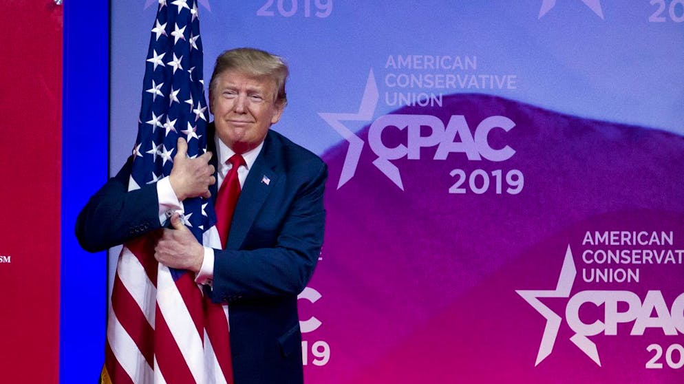 President Donald Trump hugs the American flag as he arrives to speak at Conservative Political Action Conference, CPAC 2019, in Oxon Hill, Md., Saturday, March 2, 2019. (AP Photo/Jose Luis Magana)