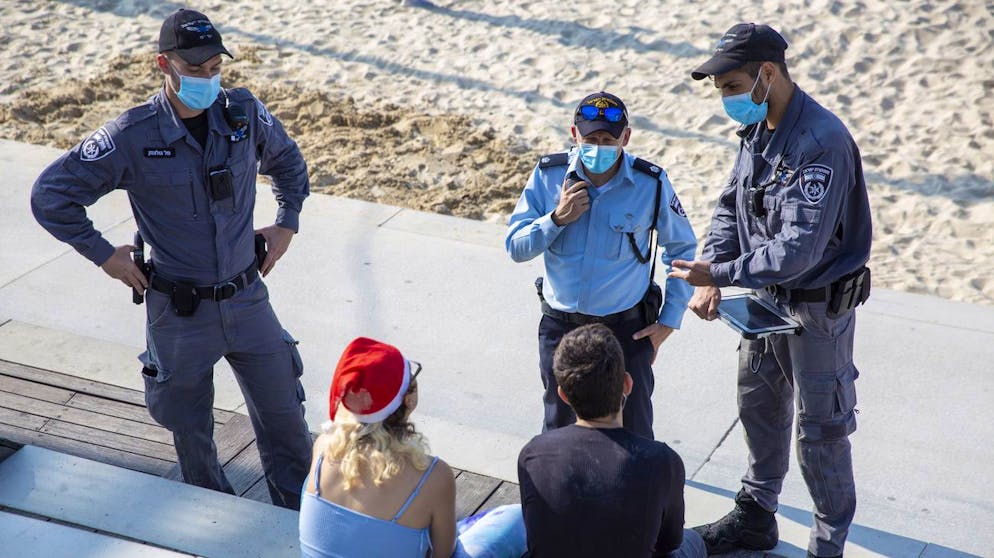 Israeli police officers ask people to leave form the beach front during the third nationwide coronavirus lockdown in Tel Aviv, Friday, Jan. 1, 2021. (AP Photo/Ariel Schalit)