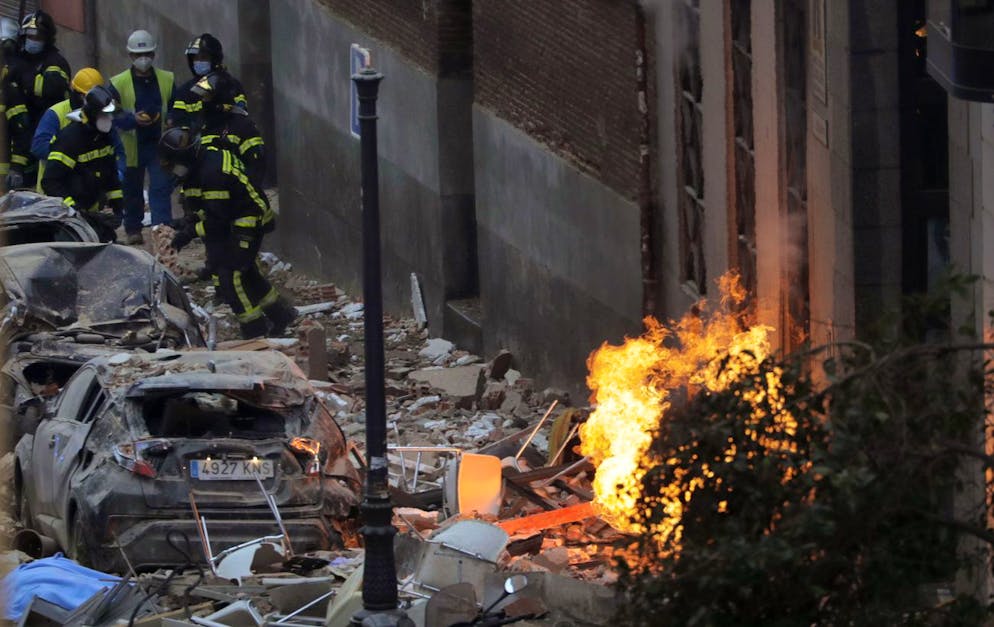 Firefighters work next to a damaged building at Toledo Street following an explosion in downtown Madrid, Spain, Wednesday, Jan. 20, 2021. A loud explosion of unknown origin has partially destroyed a six-floor-tall building flanked by a school and a nursing home in the center of Spain's capital, Madrid. (AP Photo/Manu Fernandez)
