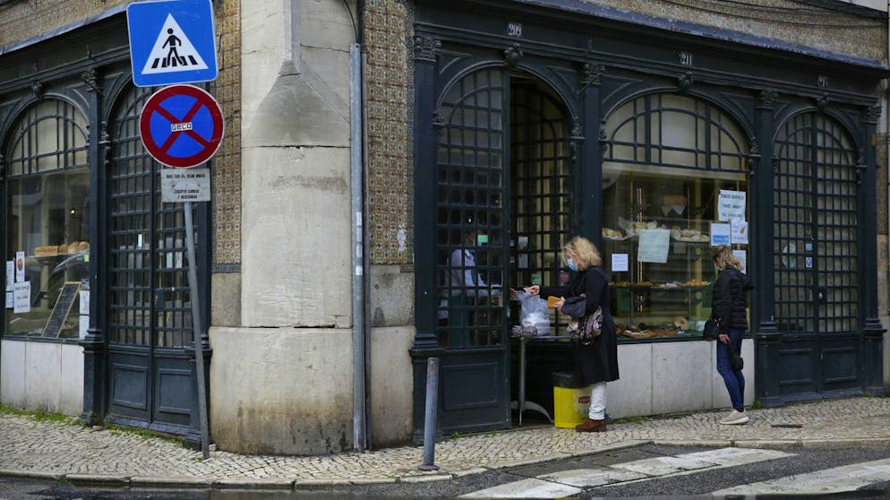 A woman buys food at the door of a pastry shop in Lisbon, Wednesday, Jan. 20, 2021. The pandemic has gained momentum in Portugal since Christmas, when restrictions on gatherings and movement were eased for four days. Restaurants and cafes are only allowed to serve food for takeaway. (AP Photo/Armando Franca)