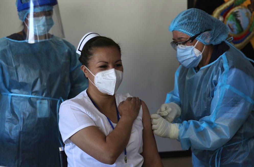 Nurse Cristina Chango receives her first dose of the Pfizer-BioNtech vaccine against COVID-19 at the Pablo Arturo Suarez Hospital in Quito, Ecuador, Thursday, Jan. 21, 2021. (AP Photo/Dolores Ochoa)