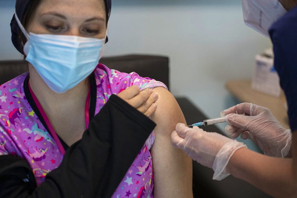 A healthcare worker receives a second dose of a COVID-19 vaccine at the Posta Central Hospital in Santiago, Chile, Wednesday, Jan. 13, 2021. (AP Photo/Esteban Felix)