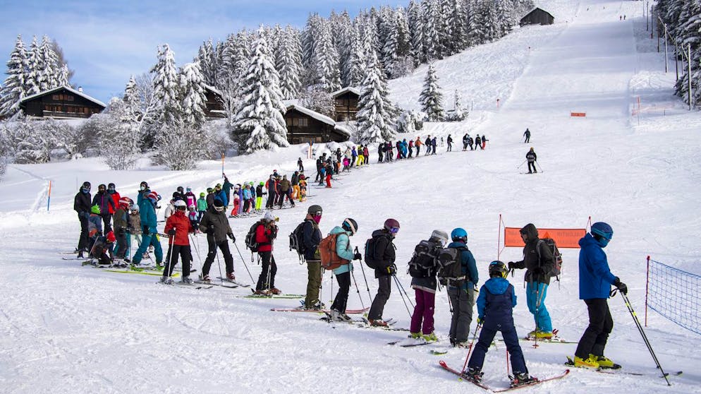 Des skieurs font la queue pour le teleski, en remontant sur la piste de ski afin de garder les distances, sur le domaine skiable des alpes vaudoises lors de la crise du Coronavirus (Covid-19) le samedi 16 janvier 2021 a La Lecherette pres du Col des Mosses. (KEYSTONE/Jean-Christophe Bott)