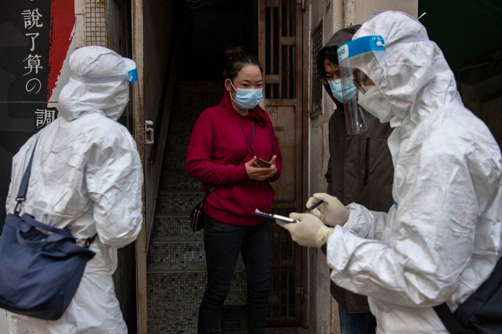 epa08963433 Civil servants check a local resident for her negative Covid-19 test results before allowing her outside, in Jordan district in Hong Kong, China, 25 January 2021. The Hong Kong government lifted the coronavirus lockdown restrictions on several blocks in Jordan districts where old and dilapidated buildings had been at the center of a Covid-19 outbreak. EPA/JEROME FAVRE