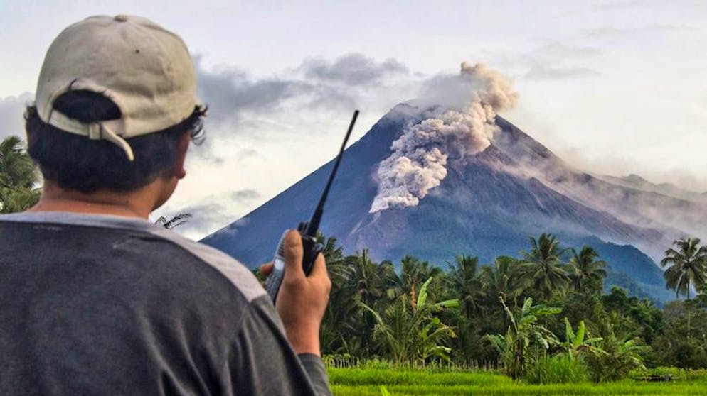 Bilder des Tages. Banger Blick zum Horizont: Ein freiwilliger Helfer benutzt sein Walkie-Talkie, während er den Vulkan Mount Merapi während einer Eruption überwacht. Der Vulkan, der als einer der gefährlichsten der Welt gilt, ist erneut ausgebrochen und spukte mehrere Stunden glühende Asche und Gestein. (27.1.2021)
