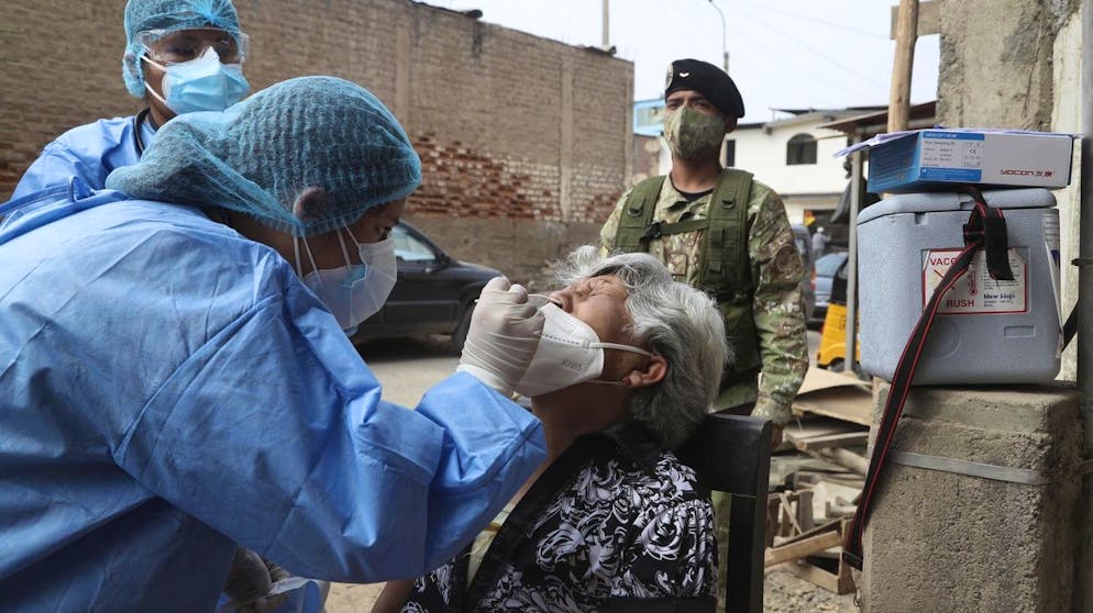 Escorted by a soldier, doctors take a sample from Graciela Cuba, 67, during a house-to-house COVID-19 testing campaign in the Villa Maria del Triunfo shantytown of Lima, Peru, Tuesday, Jan. 12, 2021. As the number of infected continues to rise in Peru, soldiers accompany healthcare workers to assist with compliance and security during a massive testing effort across the capital. (AP Photo/Martin Mejia)