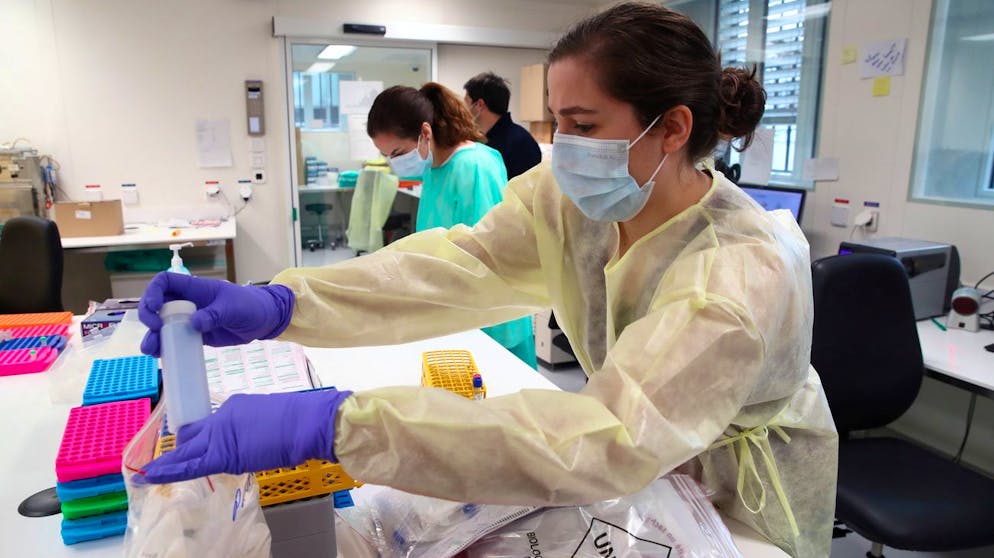 Staff members work as media visit the Microbiology Laboratory of the University Hospital (CHUV) during the coronavirus disease (COVID-19) outbreak in Lausanne, Switzerland, March 23, 2020. (KEYSTONE/REUTERS POOL/Denis Balibouse)