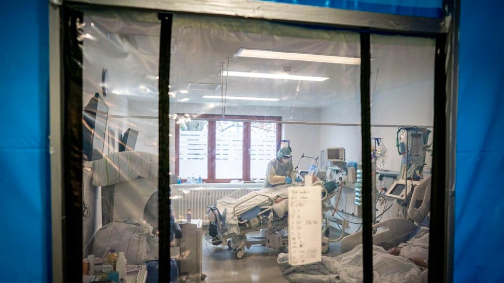 ARCHIV - 11.11.2020, Berlin: Intensivpfleger Sebastian betreut hinter einer Schleuse in einer Schutzausrüstung mit Mund-Nasenbedeckung, Gesichtsschutz, Kittel und Haube auf der Intensivstation des Krankenhauses Bethel einen Corona-Patienten. Der Patient liegt im künstlichen Koma und wird beatmet. Die Zahl der verzeichneten Todesfälle in Zusammenhang mit dem Coronavirus ist in Deutschland sprunghaft gestiegen und hat einen neuen Höchststand erreicht. Binnen eines Tages übermittelten die deutschen Gesundheitsämter dem Robert Koch-Institut (RKI) 952 neue Todesfälle, wie aus den RKI-Zahlen vom Mittwochmorgen (16.12.2020) hervorgeht. Foto: Kay Nietfeld/dpa +++ dpa-Bildfunk +++ (KEYSTONE/DPA/Kay Nietfeld)