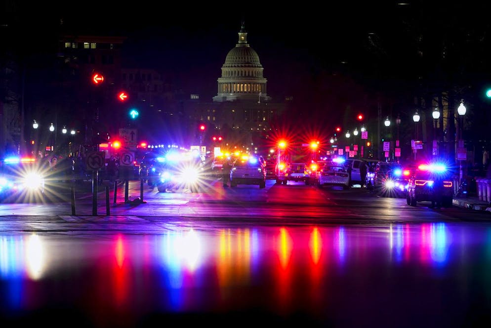 Irruzione dei fan di Trump a Capitol Hill. Con il Campidoglio degli Stati Uniti sullo sfondo, le luci dei veicoli della polizia illuminano Pennsylvania Avenue a Washington, una volta che finalmente l'edificio è stato sgomberato.
