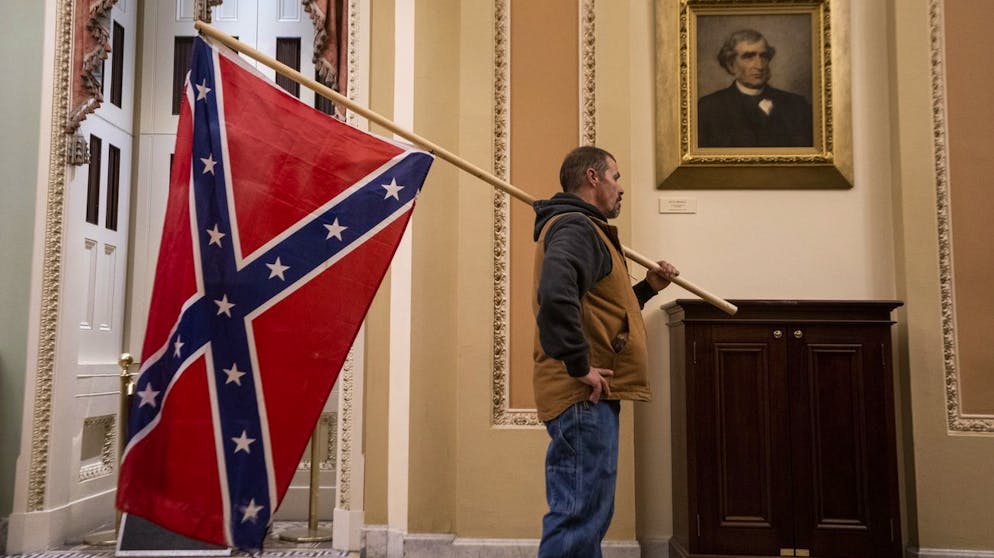 Gewalt in Washington: Trumps Mob stürmt das Kapitol. Dieser Mann führt die in den USA schon lange umstrittene Südstaatenflagge mit sich. (6. Januar 2021)