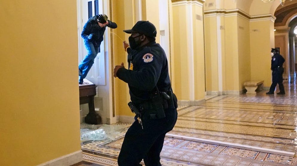 Gewalt in Washington: Trumps Mob stürmt das Kapitol. Ein Polizist des United States Capitol Police Department versucht einen durch ein eingeworfenes Fenster eindringenden Mann mit Pfefferspray zurückzudrängen. (6. Januar 2021)