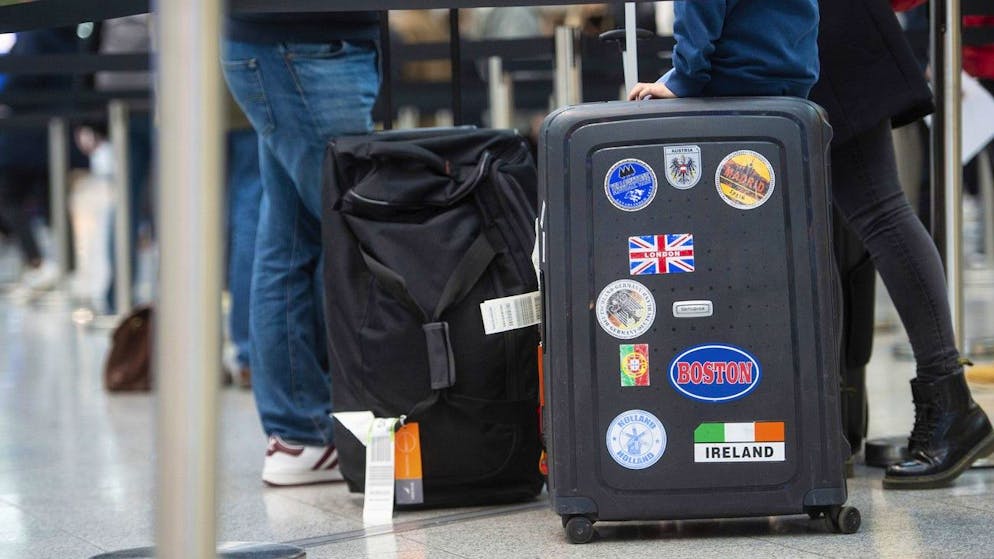 A family queues with their luggage at the airport in Duesseldorf, Germany, for a Corona test, while a British flag with the words