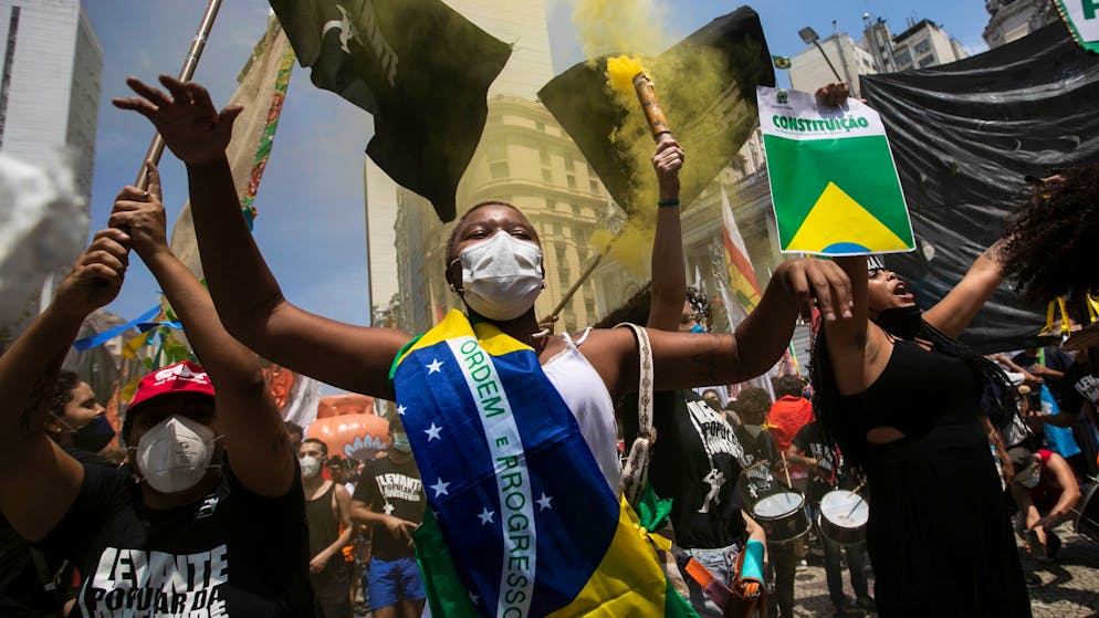 A woman, wrapped in a Brazilian national flag, chats slogans during a protest against Brazilian President Jair Bolsonaro calling for his impeachment over his government’s handling of the pandemic and accusations of corruption in the purchases of COVID-19 vaccines, in Rio de Janeiro, Brazil, Saturday, Oct. 2, 2021. (AP Photo/Bruna Prado)