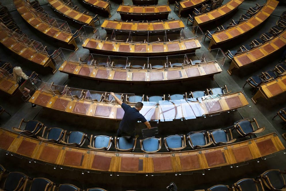 Fabio Arati, Mitarbeiter der Parlamentsdienste, montiert die Plexiglasscheiben bei den Pulten der Nationalraete ab, am Montag, 4. Oktober 2021, im Nationalrat in Bern. Das Parlament hat in der abgelaufenen Session die Zertifikatspflicht im Bundeshaus beschlossen. Als Folge davon koennen die Plexiglasscheiben bei den Pulten der Raete entfernt werden. (KEYSTONE/Peter Klaunzer)