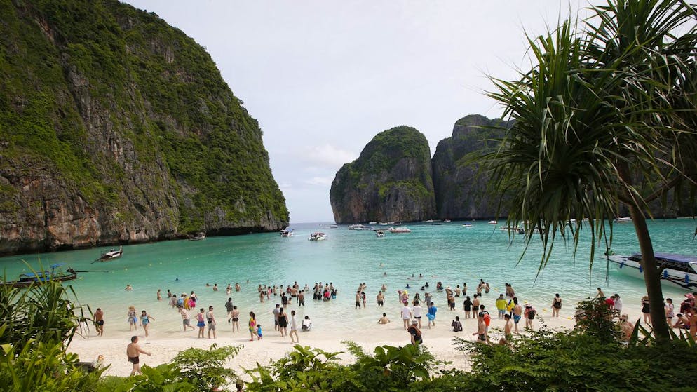 Tourists walk the beach of Maya Bay, Phi Phi Leh island in Krabi province, Thailand, Thursday, May 31, 2018. The popular tourist destination of Maya Bay in the Andaman Sea will close to tourists for four months from Friday to give its coral reefs and sea life a chance to recover from an onslaught that began nearly two decades ago. (AP Photo/Sakchai Lalit)