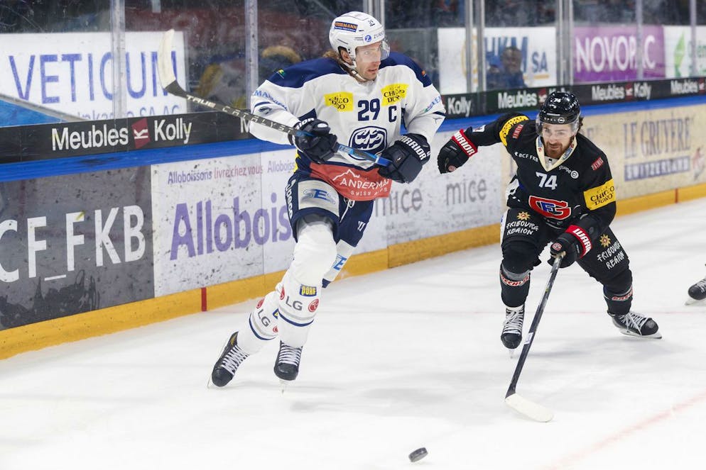 Le defenseur tessinois Michael Fora, gauche, lutte pour le puck avec l'attaquant fribourgeois Jordann Bougro, droite, lors du match du championnat suisse de hockey sur glace de National League LNA, entre le Fribourg Gotteron, FGHC, et le HC Ambri-Piotta ce samedi, 23 octobre 2021 a la patinoire BCF Arena de Fribourg. (KEYSTONE/Cyril Zingaro)