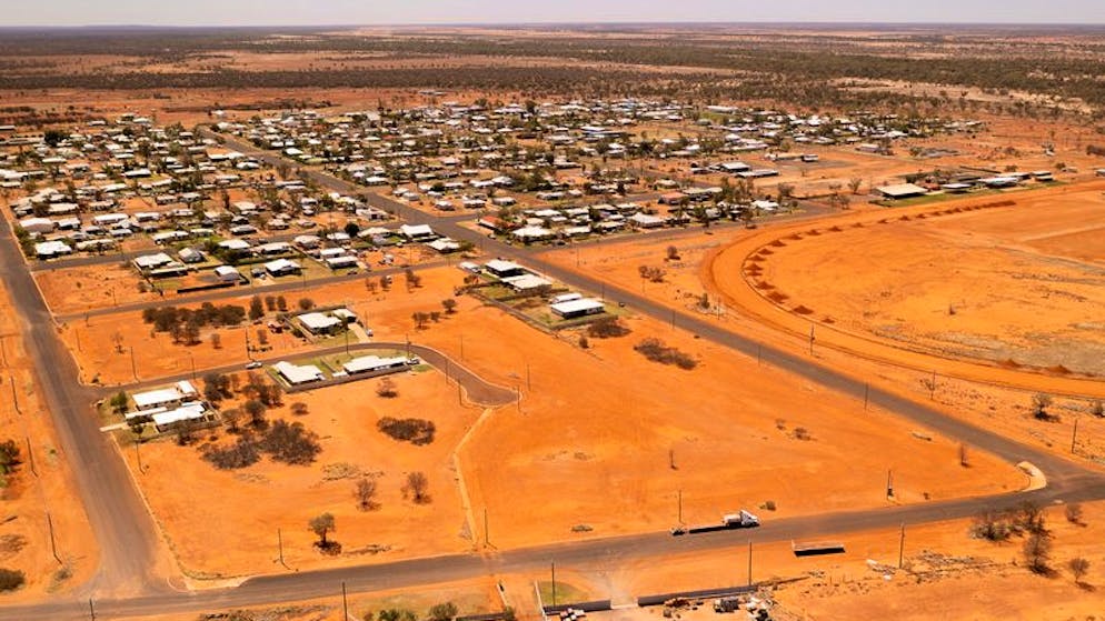 02.10.2021, Australien, Quilpie: Das Outback-Dorf aus der Luft, umgeben von roter Erde und spärlicher Vegetation. Um der Wohnungsnot zu begegnen und dringend benötigte Arbeitskräfte anzulocken hatte der Gemeinderat eine Idee: Er beschloss kurzerhand, Landparzellen kostenfrei zur Verfügung zu stellen - falls Interessenten sich bereit erklärten, auf den 1000 Quadratmeter großen Grundstücken ein Haus zu bauen und dort mindestens sechs Monate zu leben. Die Behörden wurden von Anfragen geradezu überrollt. Foto: Leon O'Neil via AP/dpa +++ dpa-Bildfunk +++