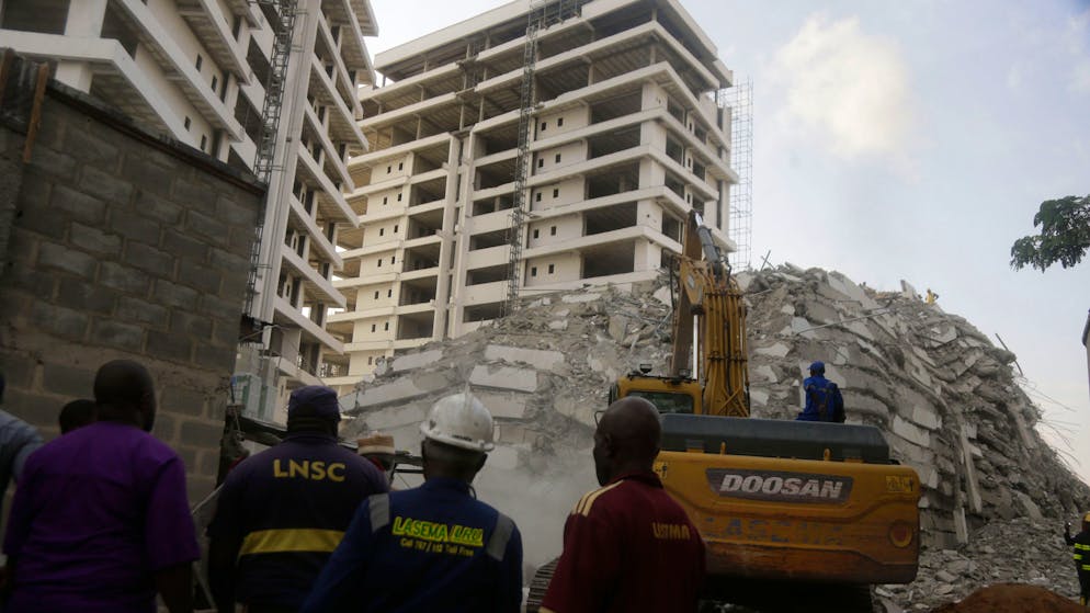 Rescue workers are seen at the site of a collapsed 21-story apartment building under construction in Lagos, Nigeria, Monday, Nov. 1, 2021. At least two people were killed and dozens more remain missing after the collapse of a 21-story apartment building being built in an upscale area of Nigeria's largest city, witnesses said on Monday.(AP Photo/Sunday Alamba)