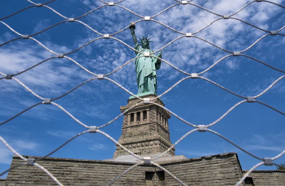 epa08557069 The Statue of Liberty on Liberty Island seen through a fence in New York, New York, USA, 20 July 2020. Liberty Island, which is operated by the National Parks Service, is reopening to visitors today for the first time since being closed in March due to the coronavirus pandemic, though there will no access inside of the Statue of Liberty, the island's museum, or to Ellis Island. EPA/JUSTIN LANE