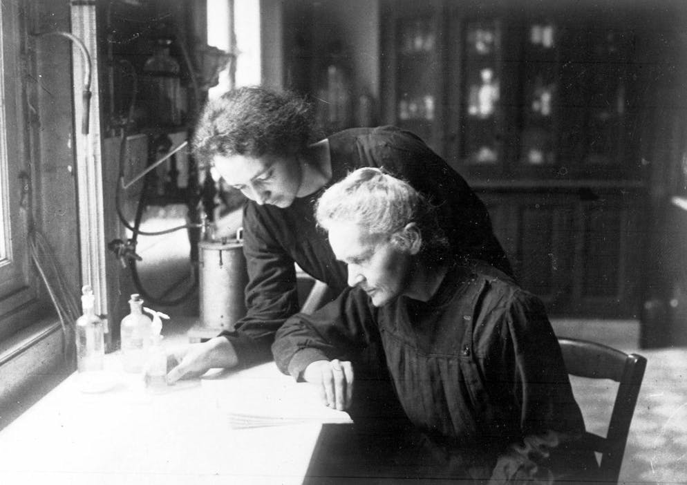 La physicienne et chimiste franco-polonaise Madame Marie Curie, assise à l'avant, travaille dans un laboratoire, avec sa fille Irène, à Paris France, le 20 avril 1927.