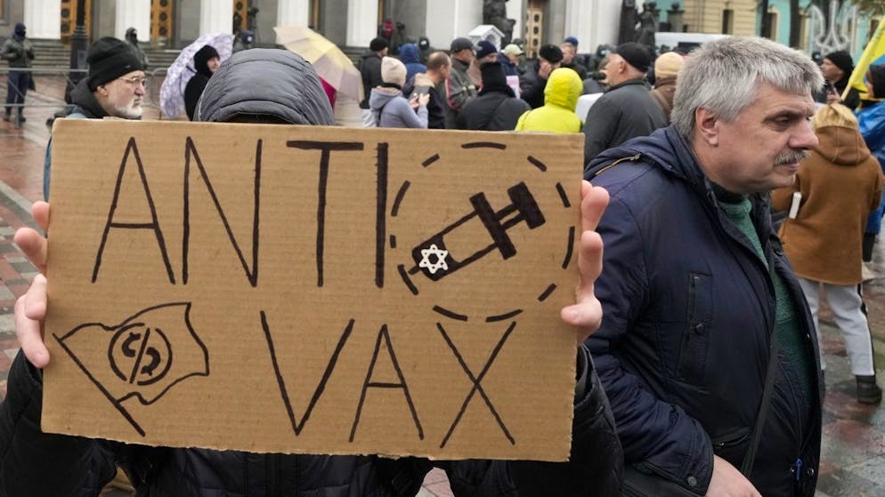 A demonstrator holds an anti-vax sign with antisemetic imagery during a protest against COVID-19 restrictions and vaccine mandates in Kyiv, Ukraine, Wednesday, Nov. 3, 2021. In a bid to stem contagion, Ukrainian authorities have required teachers, government employees and other workers to get fully vaccinated by Nov. 8 or face having their salary payments suspended. In addition, proof of vaccination or a negative test is now required to board planes, trains and long-distance buses. (AP Photo/Efrem Lukatsky)